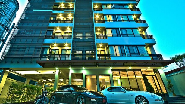 A multi-story hotel with a modern design, featuring balconies on each floor, a central staircase, and a covered entrance area. - The Present Sathorn (Bangkok)