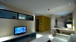 A modern living room with a flat-screen TV, a white sofa, and a dining area with a table and chairs. - The Present Sathorn (Bangkok)
