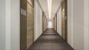 A long, narrow hallway with doors marked with numbers, likely indicating room numbers. - The Present Sathorn (Bangkok)