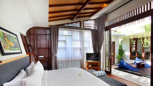 A hotel room with a bed, a television, and a view of the outdoor area.