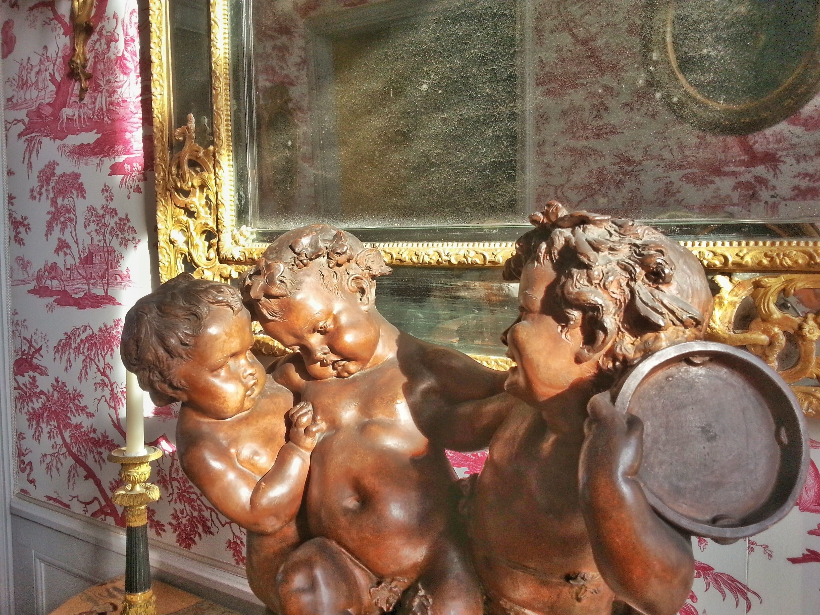 Une statue de petits anges, avec une bougie et un bassin.