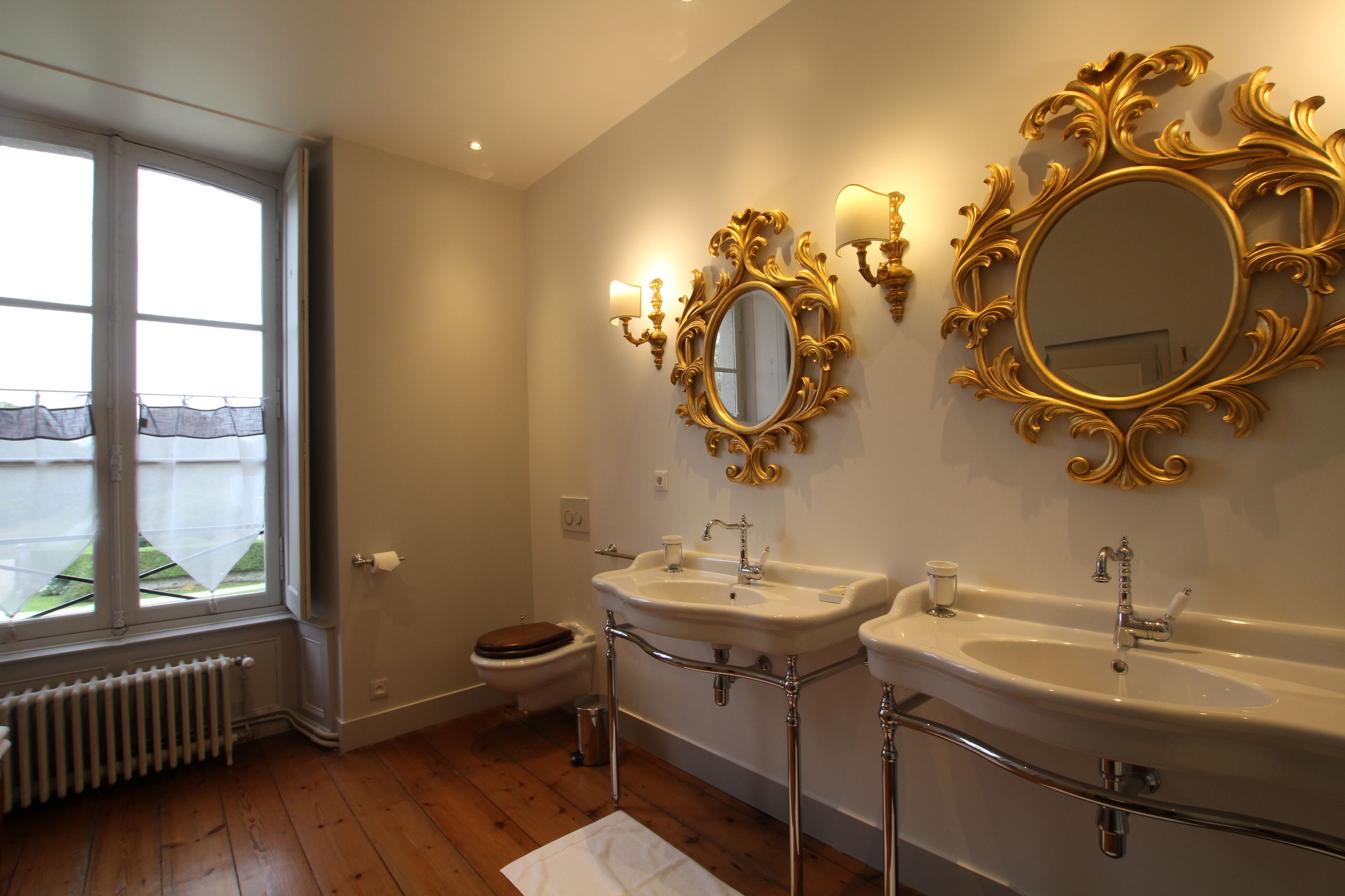 Une salle de bain avec deux lavabos, des toilettes et une fenêtre donnant sur un beau paysage.