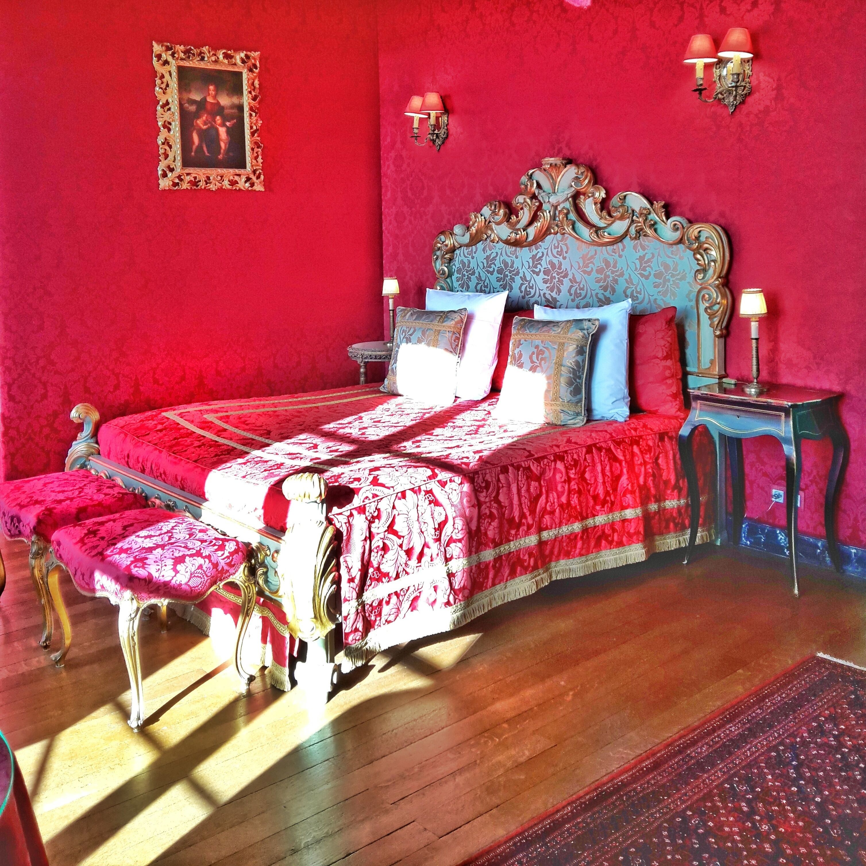 Una habitación con una cama grande, un cabecero ornamentado y una alfombra roja.