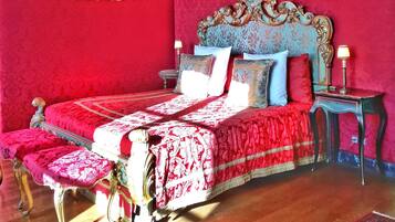 Una habitación con una cama grande, un cabecero ornamentado y una alfombra roja.