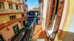 A narrow alleyway with a wooden floor, a metal railing, and buildings on either side. There is a sign for 'Unicaja' on the left and a colorful structure in the background. - The Lights Hostel (Málaga)