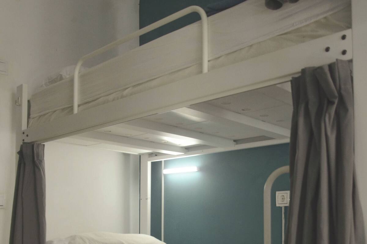 Una cama individual con cabecera, mesita de noche y cajón.