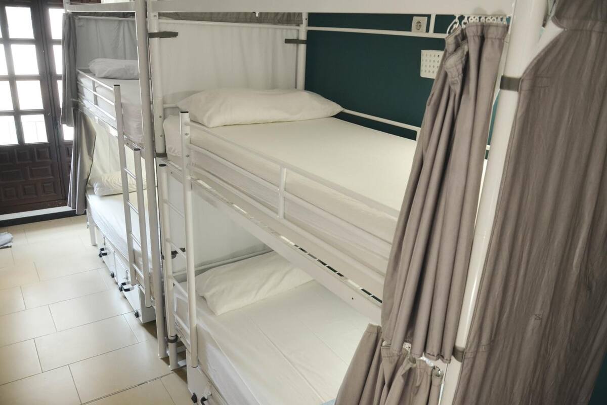 Una habitación con literas, una ventana con cortinas y una pared verde.