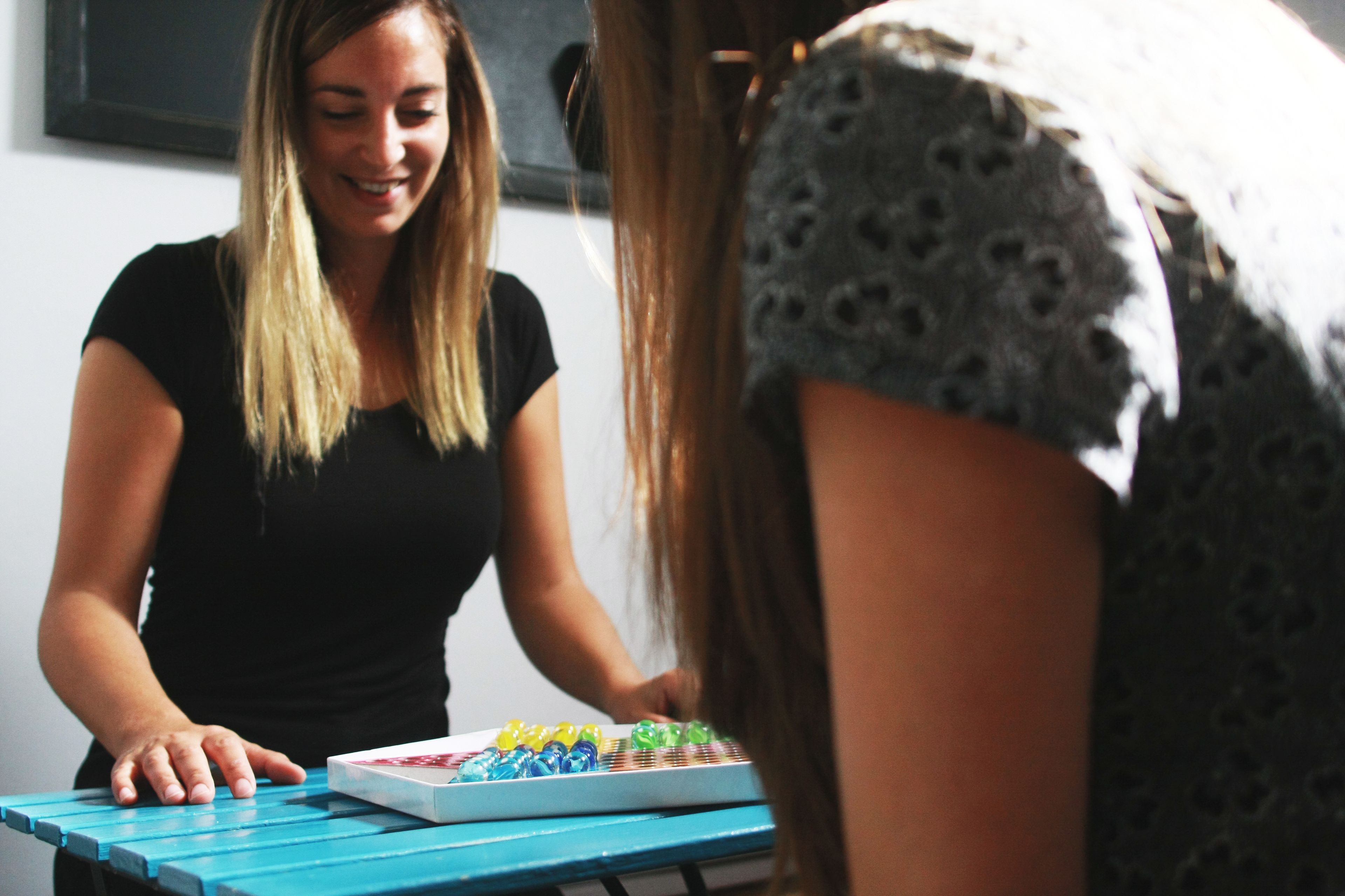 Une personne se tient debout près d’une table sur laquelle est posé un jeu de société.