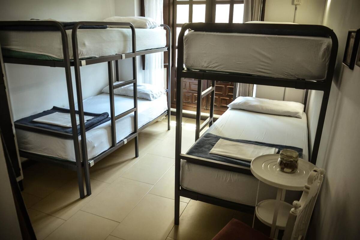 Un dormitorio con literas, una mesita con una vela y una ventana con vistas al exterior.
