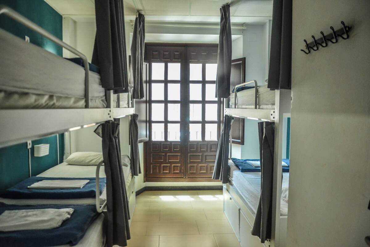 Un dormitorio con literas, una puerta de madera y un ventanal.