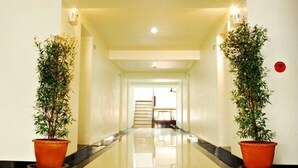 Un pasillo de hotel con piso pulido, una escalera al final y plantas en macetas a ambos lados.