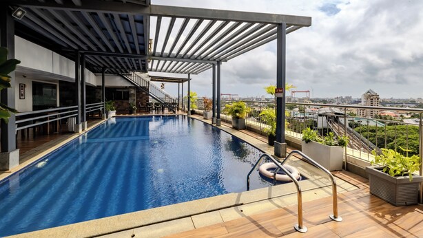 A rooftop pool with a view of the cityscape, including a bridge and buildings. - Olive Downtown Kochi (Kanayannur)