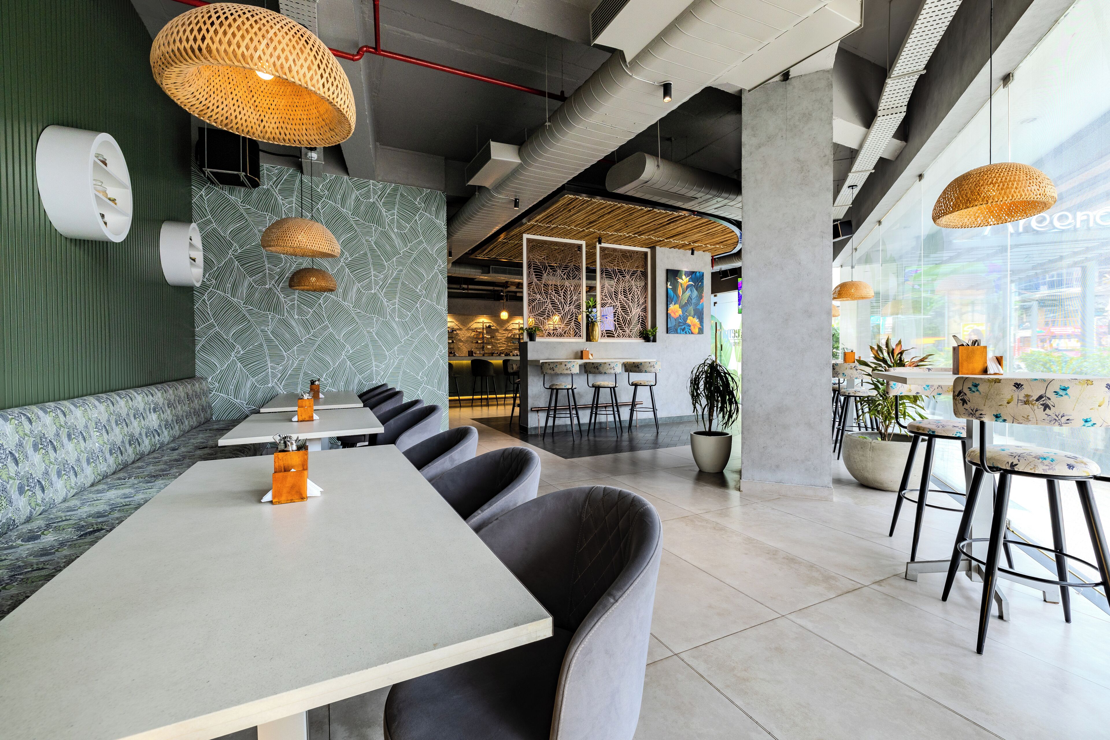 A modern restaurant interior with high ceilings, exposed ductwork, and a mix of seating arrangements including bar stools and booths.