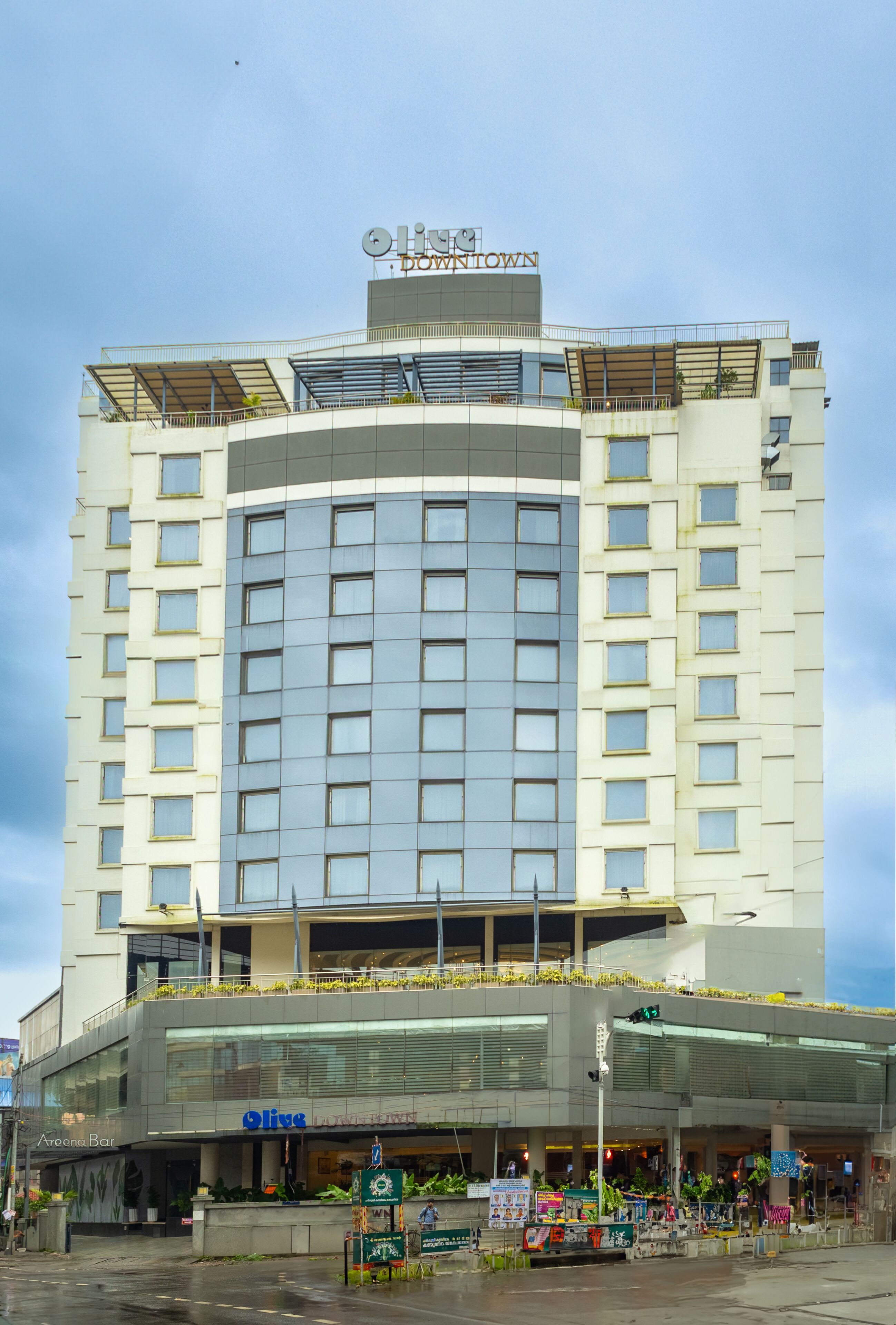 A hotel with a modern design, featuring a large glass facade and a rooftop terrace.