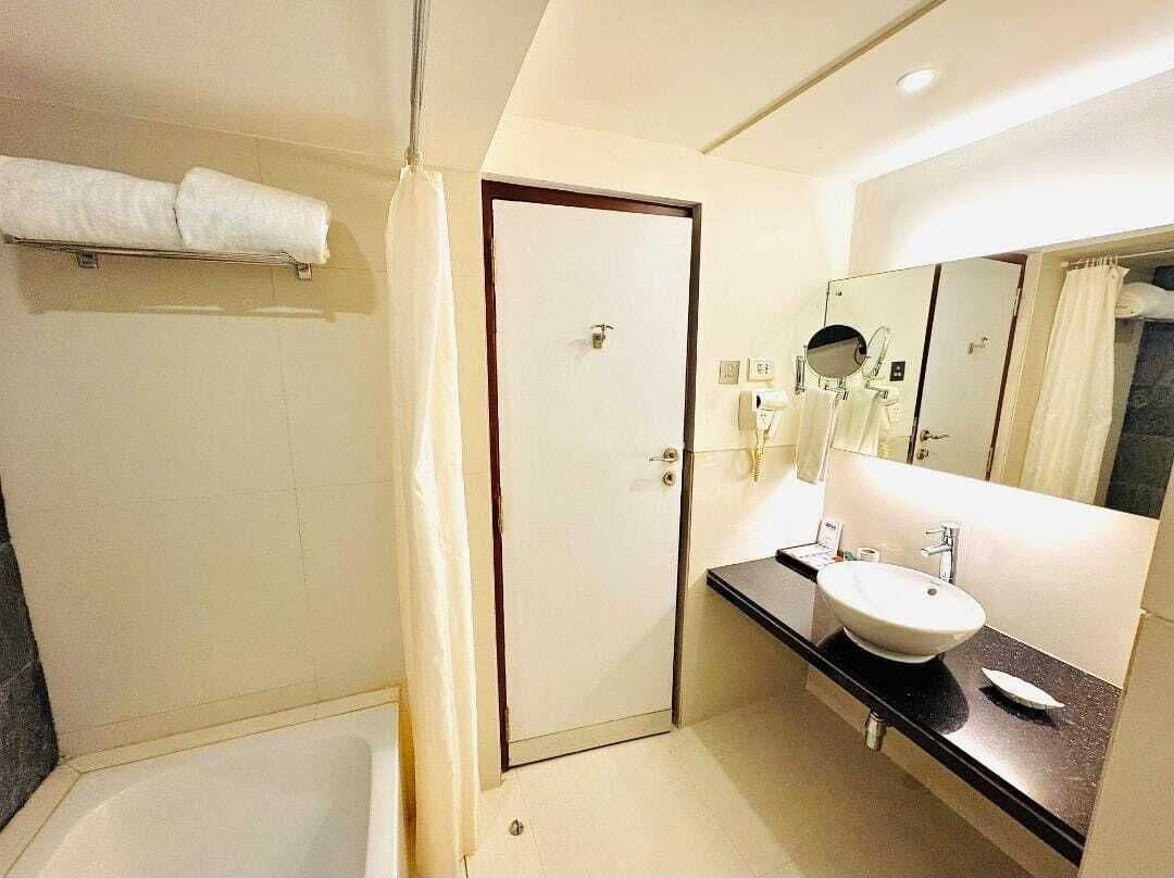 Un baño moderno con un lavamanos blanco, un espejo grande y una zona de ducha.