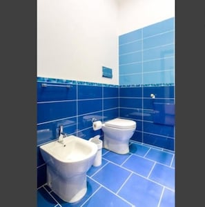 A bathroom with blue tiles, a white sink, and a toilet.