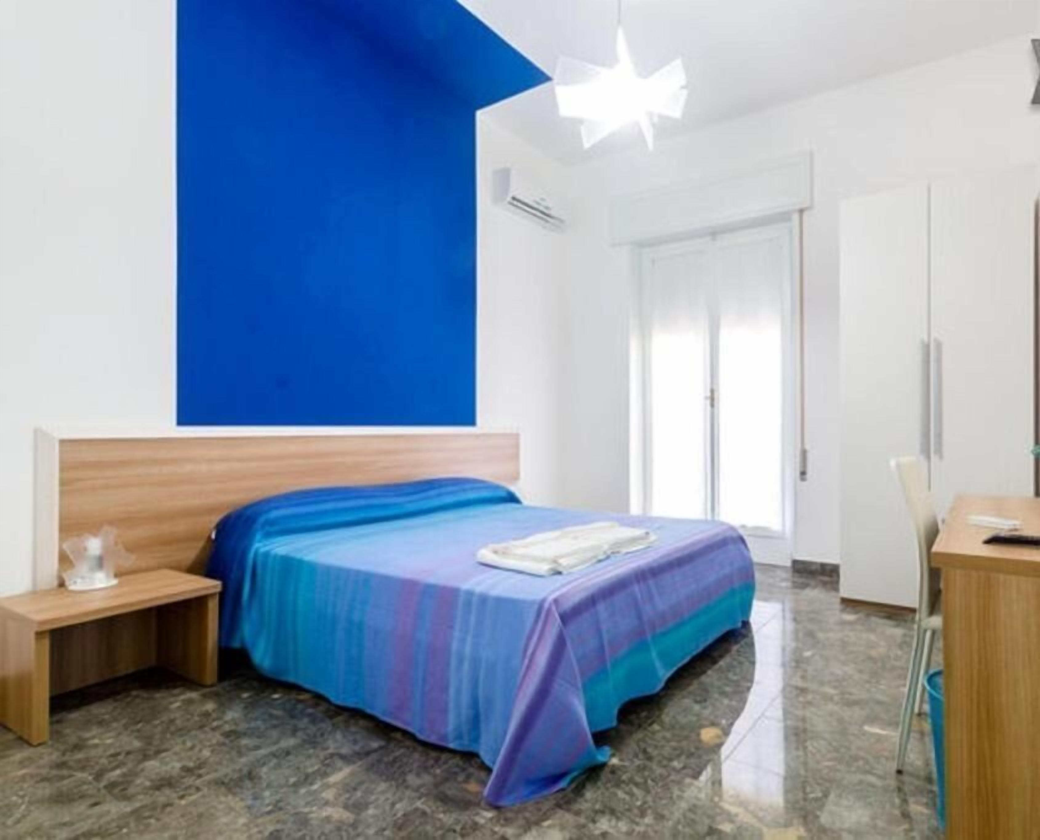 Un dormitorio con una cama, una mesita de noche, un escritorio y una silla.