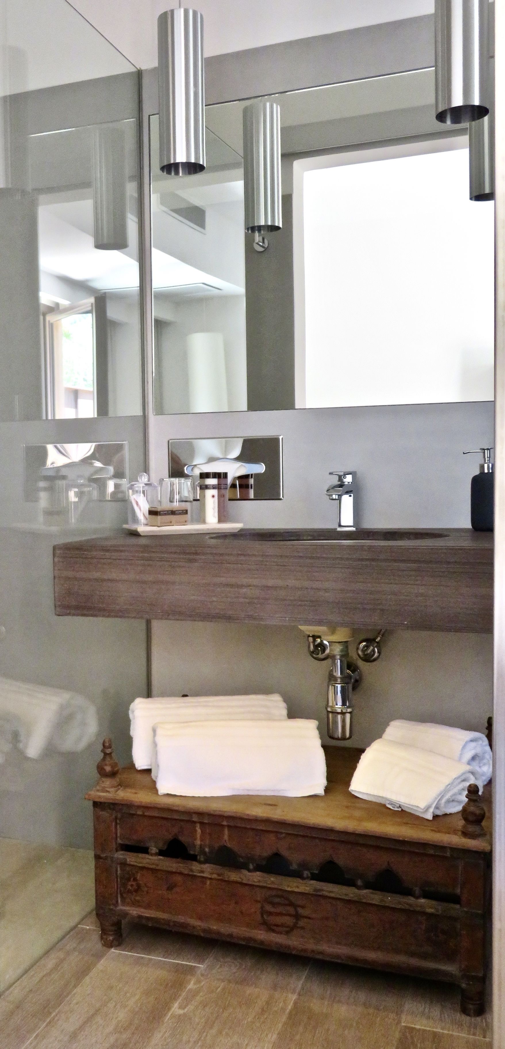 A bathroom with a wooden vanity, a large mirror, and a modern faucet.