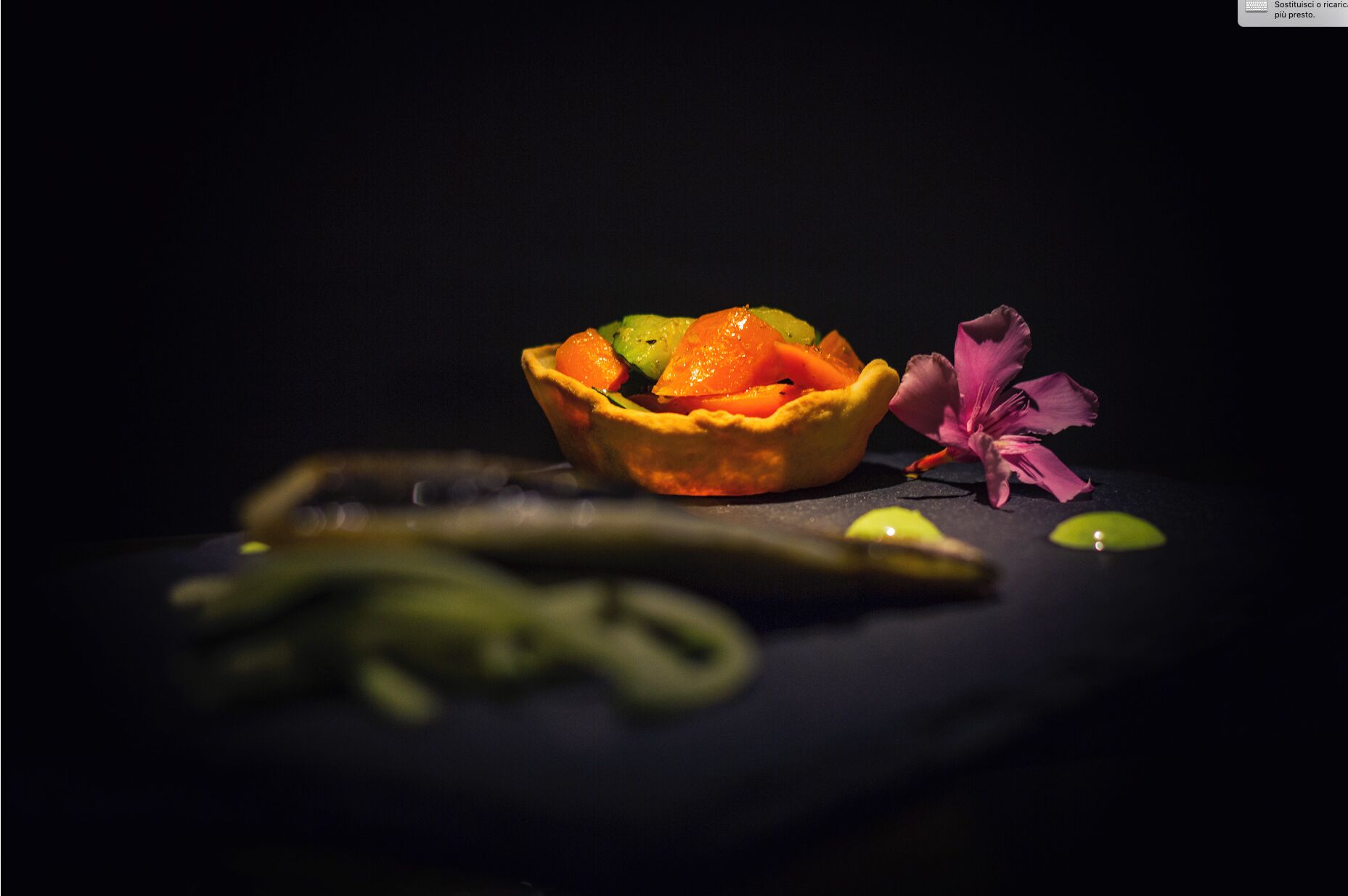 Ein Dessert mit Mürbeteigboden, Orangenscheiben und einer Blüte auf dunklem Untergrund.