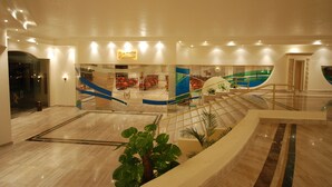 A spacious lobby with a marble floor, a central staircase, and a seating area with tables and chairs. - Life Resort Coral Hills - All inclusive (El Quseir)