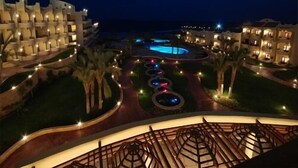 A resort with multiple buildings, a swimming pool, and a well-lit walkway. - Life Resort Coral Hills - All inclusive (El Quseir)