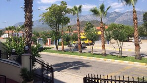 A street view with palm trees, a yellow bus, and buildings with red roofs. - Stella Hotel (Kemer)