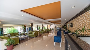 A hotel lobby with green sofas, a reception desk, and potted plants. - Stella Hotel (Kemer)