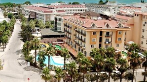 A coastal hotel with a swimming pool, palm trees, and a view of the sea. - Stella Hotel (Kemer)