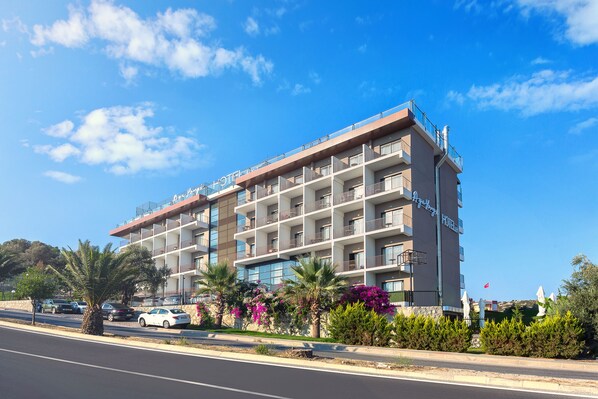 Un hotel de varios pisos con balcones, un estacionamiento y jardines ajardinados.