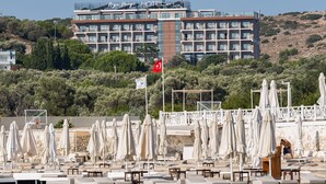 Un hôtel doté de nombreux balcons, d’un drapeau et d’un espace de plage avec des parasols et des chaises longues.