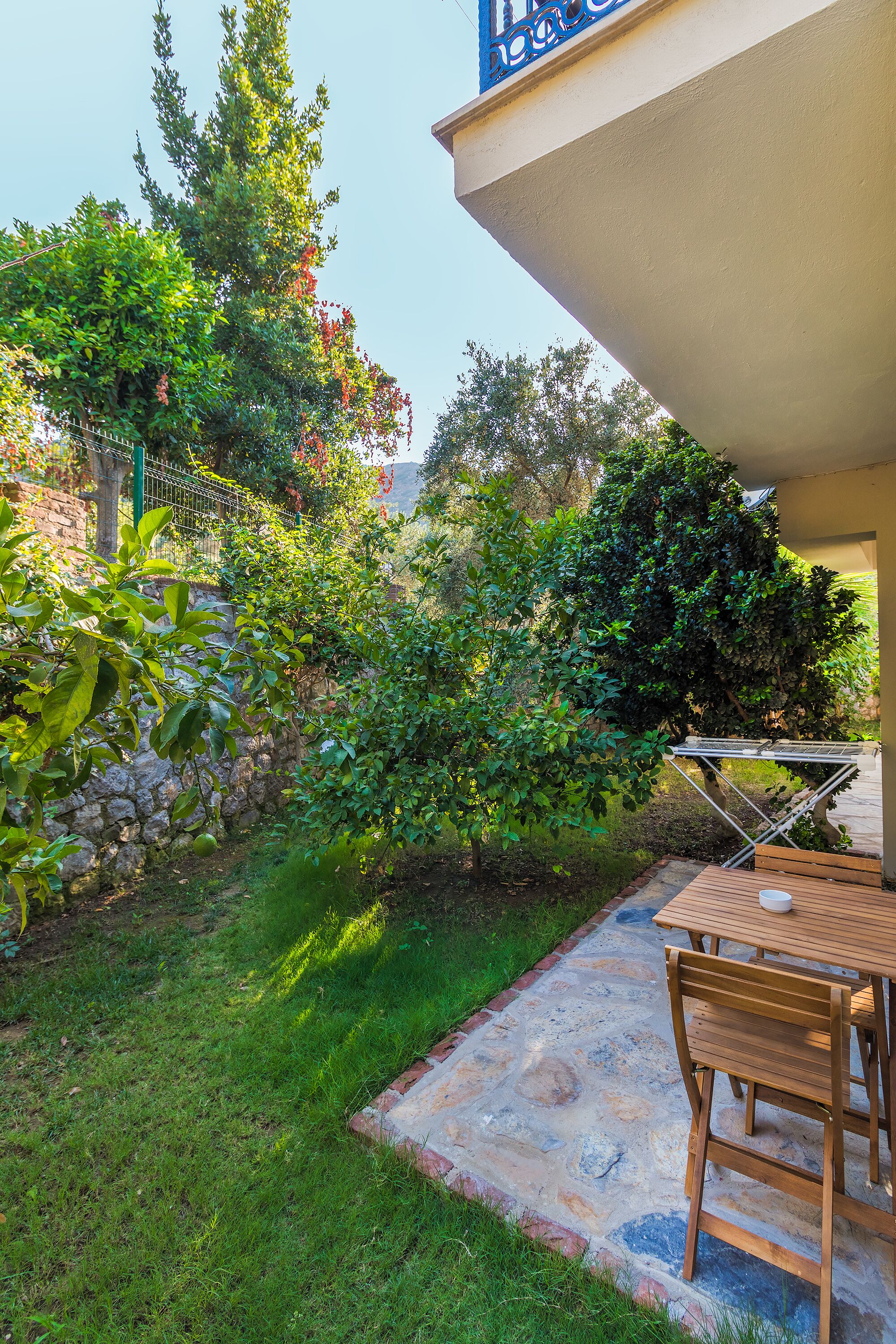 A patio area with a stone floor, a wooden table, and chairs.