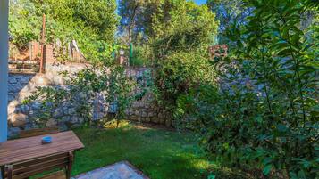A garden with a stone wall, a wooden table, and a bench.