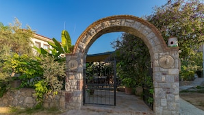 Un arco de entrada a un espacio al aire libre cubierto, con pared de piedra y plantas en macetas.