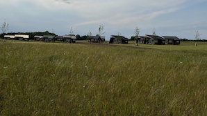 Una hilera de cabañas en un campo cubierto de hierba bajo un cielo despejado.