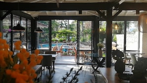 An indoor dining area with large windows overlooking a pool and garden. - Selimhan Hotel - Selimiye (Marmaris)