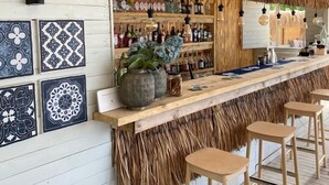 A bar area with a thatched roof, wooden shelves with bottles, and patterned tiles on the wall. - Selimhan Hotel - Selimiye (Marmaris)
