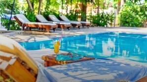 A pool area with lounge chairs and a drink on a wooden table. - Selimhan Hotel - Selimiye (Marmaris)