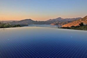 A panoramic view of a mountainous landscape with a large, clear pool in the foreground.