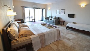 Une chambre d’hôtel avec un grand lit, un canapé, une télévision et un bureau.