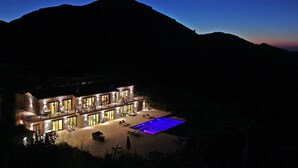 Un immeuble en pierre à plusieurs étages avec une piscine, de nuit.