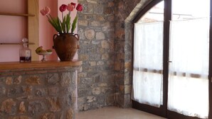 Quarto nos fundos com paredes de pedra, teto de madeira, uma janela grande e piso de azulejos.