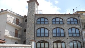 Um edifício de pedra com várias andares, janelas em arco e varandas.