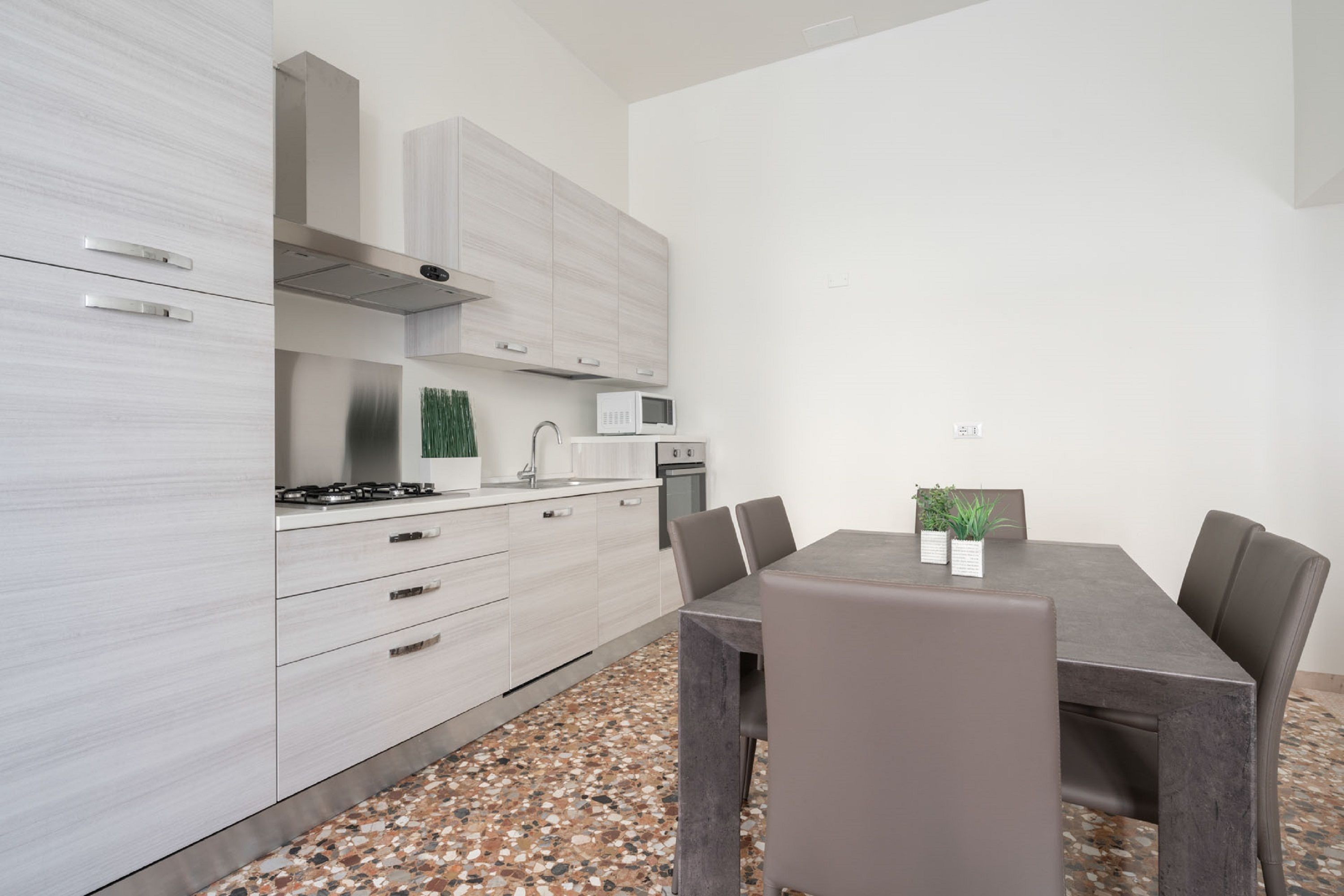 Eine moderne Küche mit weißen Schränken, einem Gasherd, einer Mikrowelle und einem Essbereich mit Tisch und Stühlen.