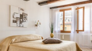A hotel room with two beds, a large window with curtains, a radiator, and a wall-mounted artwork. - Dorsoduro Charme Apartments by Wonderful Italy (Venice)