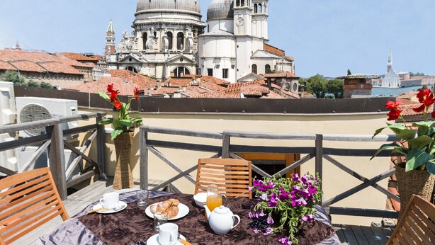 A terrace with a table set for breakfast, overlooking a historic building with domes and bell towers. - Dorsoduro Charme Apartments by Wonderful Italy (Venice)