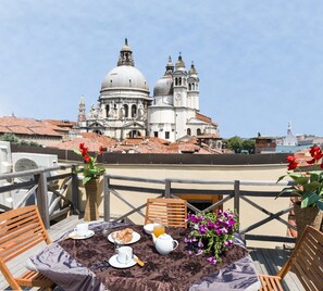 A terrace with a table set for breakfast, overlooking a historic building with domes and bell towers. - Dorsoduro Charme Apartments by Wonderful Italy (Venice)
