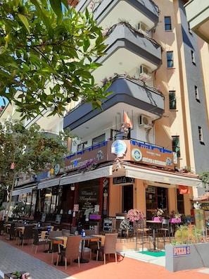 A restaurant with outdoor seating, a sign for Musti's, and a pizza sign.