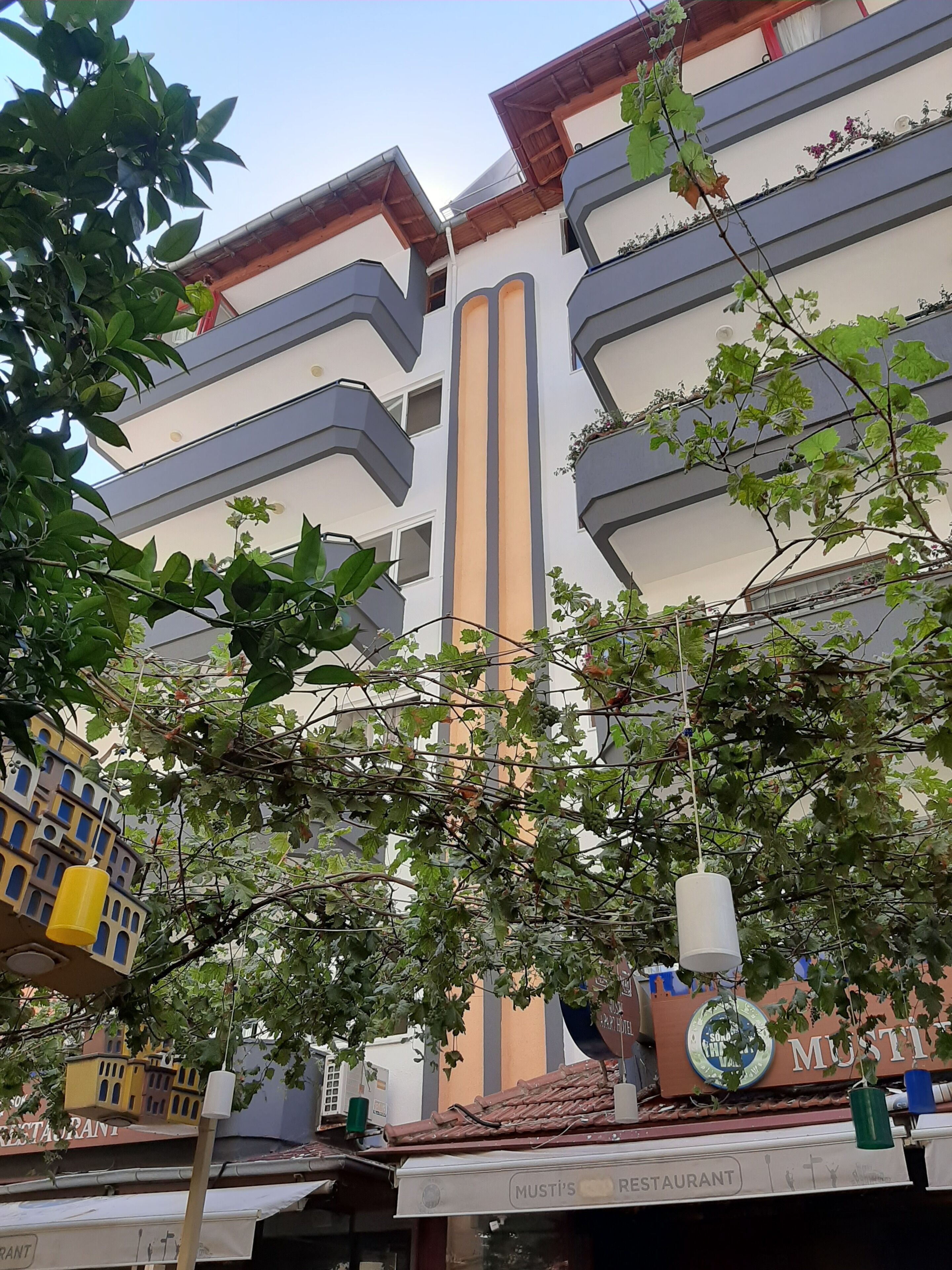 A multi-story building with balconies, a restaurant named "Musti's Restaurant" at the ground level, and a sign for "Sundae World."