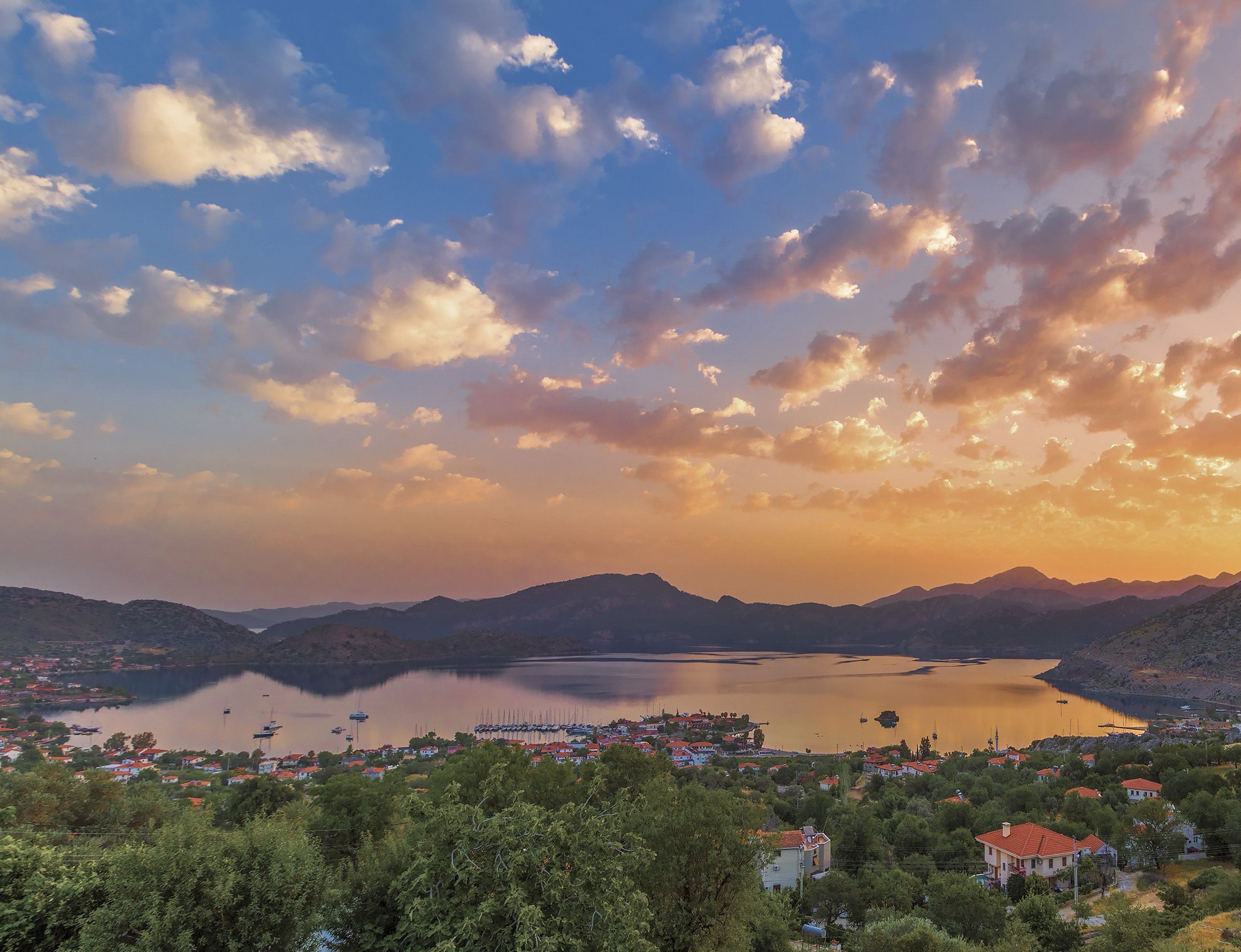 A coastal town with a lake, surrounded by hills and dense greenery.