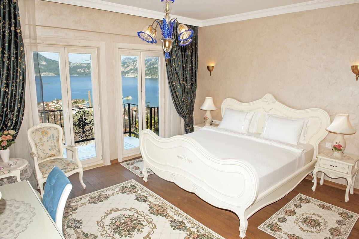 Un dormitorio con una cama grande, un candelabro, vista al mar y un balcón.